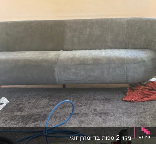 ספה אפורה עם צינור כחול ומטליות על הרצפה